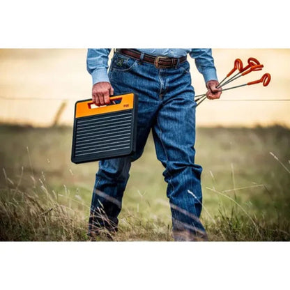 farmer holding a Gallagher S120 solar panel fence charger and posts in a field