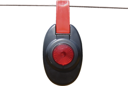 Patriot fence alert is a Black and red flashing light  hanging on a wire against a white background